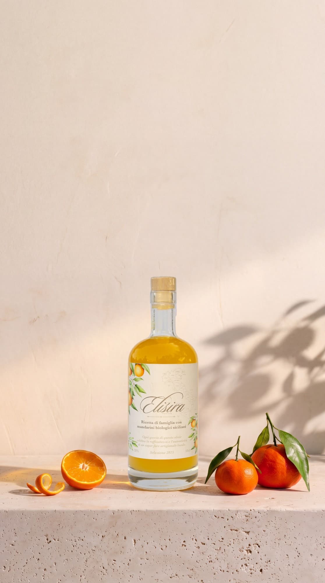 Bouteille Elisira, liqueur de mandarines siciliennes, posée sur une tablette de pierre entre des mandarines fraîches